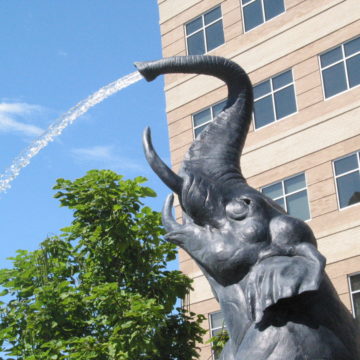 Bronze elephant on hind legs spraying water from its trunk by Daniel Ostermiller