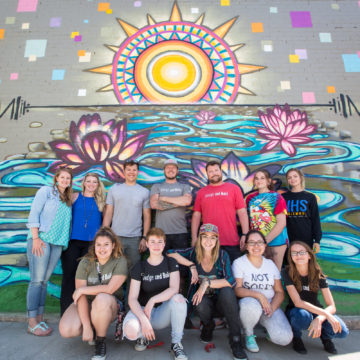 participants in the outreach program pose for a photo in front of their finished mural