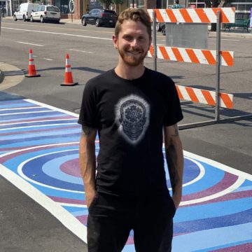 AJ Davis posing by his finished art crosswalk