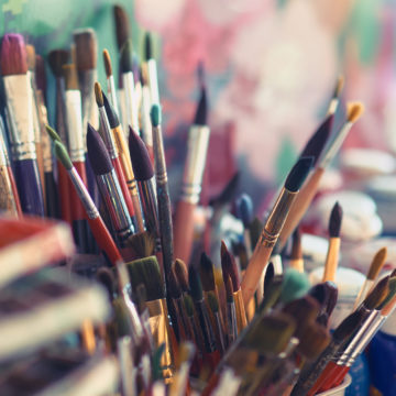 Paint brushes and watercolor paints on the table in a workshop, selective focus, close up