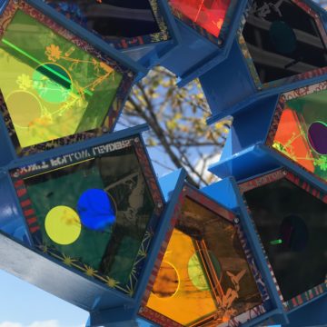 a brightly colored sculpture made by pat arron. Metal birdhouses with neon acrylic facades are stacked upon each other in a circular fashion.