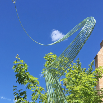 A metal green curve reaches for the sky with a glass circle at the end. Sculpture by Jeff Glode Wise
